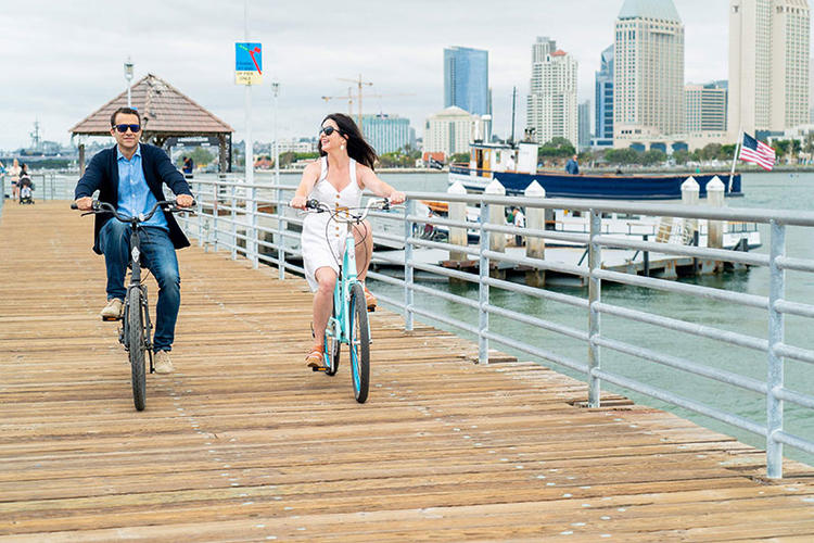 Man and woman riding bicycles after disembarking the Flagship Ferry