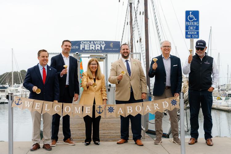Six people smiling and ringing bells at a the Chula Vista Ferry Launch Press Day